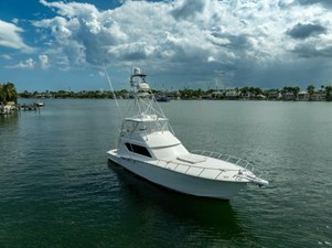 VENTURA 5 2005 Hatteras 60 Convertible yacht on calm water under cloudy sky.