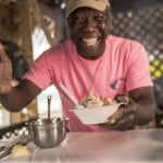 A man hands out a bowl of freshly made conch salad Bimini Eats Bahamian Gastronomy