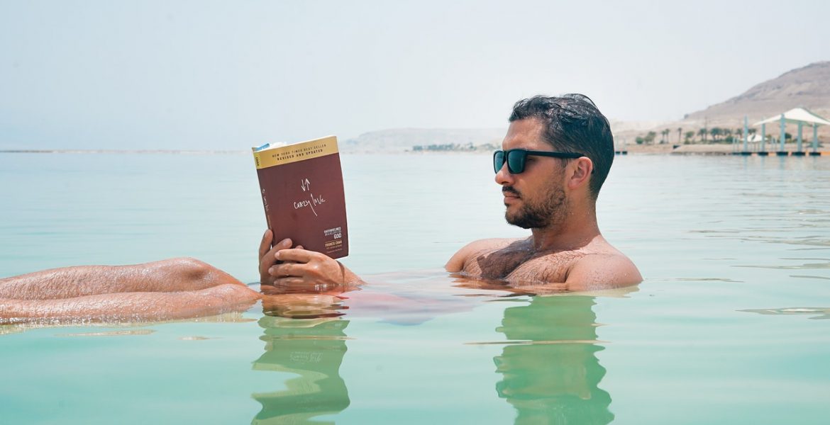 an image of a man reading in the water: what we're reading