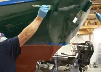 Two men paint a boat with topside