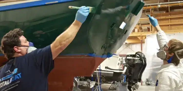 Two men paint a boat with topside