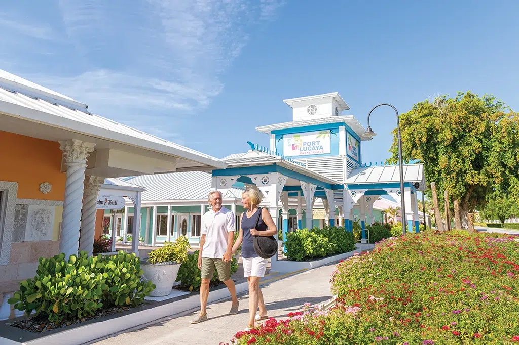 Two people smiling and walking along Grand Bahamas shops