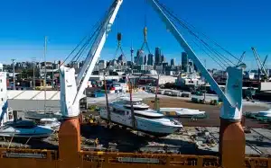 A yacht before transport at port being lifted by two cranes