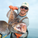 A man holds a fish showing an example of the perfect fishing photo