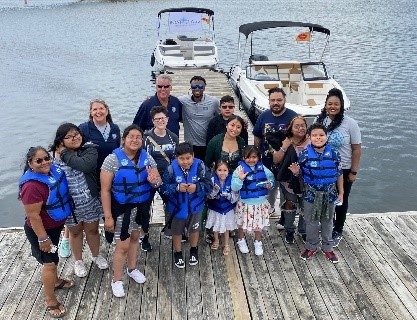 Brunswick and the attendees to their children's philanthropy on a dock in front of two boats