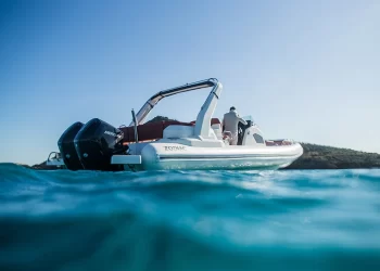 A split camera view of the Zodiac floating on water with wavy blue water on the bottom third of the image