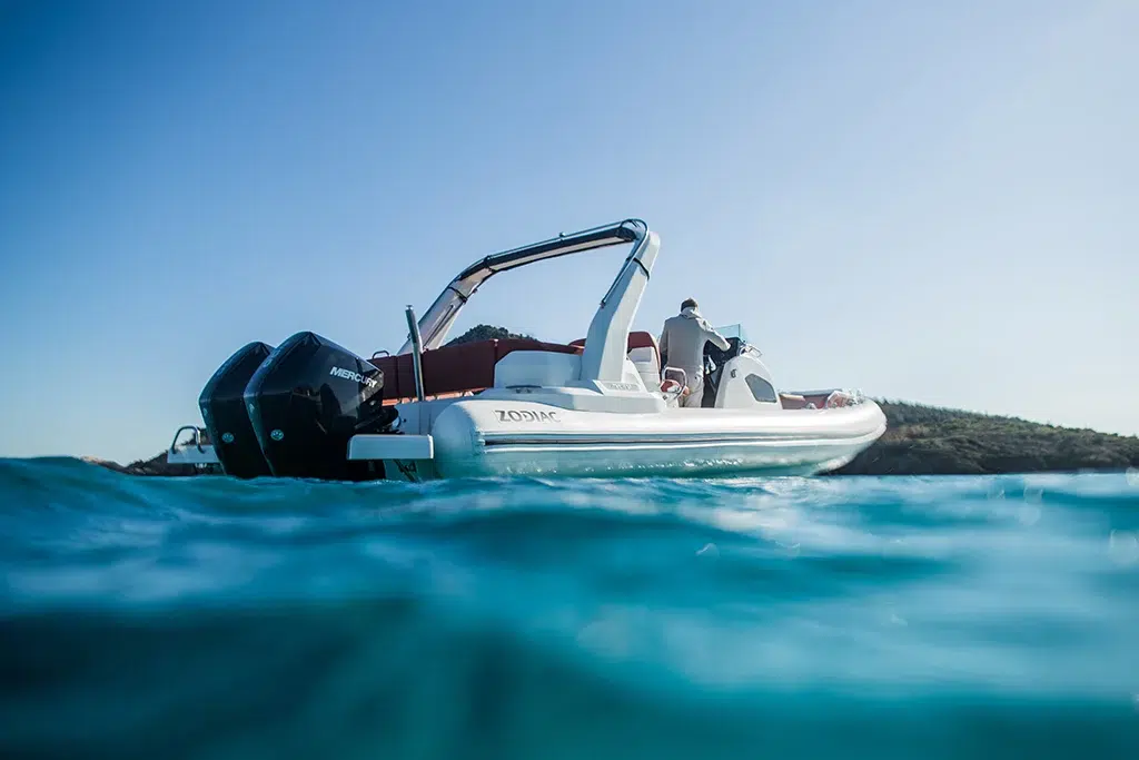 A split camera view of the Zodiac floating on water with wavy blue water on the bottom third of the image