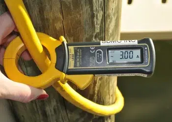 A person measuring Amps with a device on shore