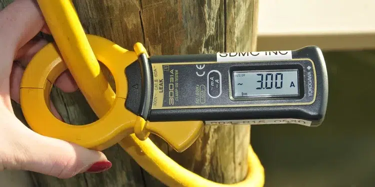 A person measuring Amps with a device on shore
