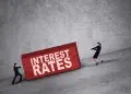 Two people struggling to carry interest rates up a slope