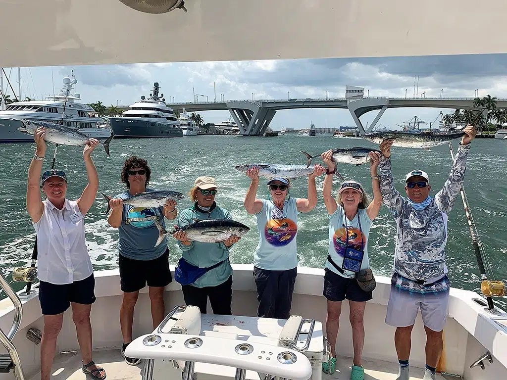 Six women holding up their catches while on a boat