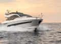 A bow side view of the Fairline Phantom 65 cutting across water during evening hours