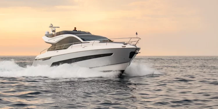 A bow side view of the Fairline Phantom 65 cutting across water during evening hours