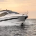 A bow side view of the Fairline Phantom 65 cutting across water during evening hours