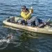 A man using a fishing kayak to reel in a fish