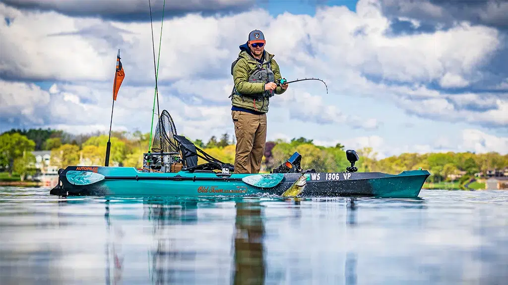 A man reels in a fish in his Oldtown Sportsman kayak