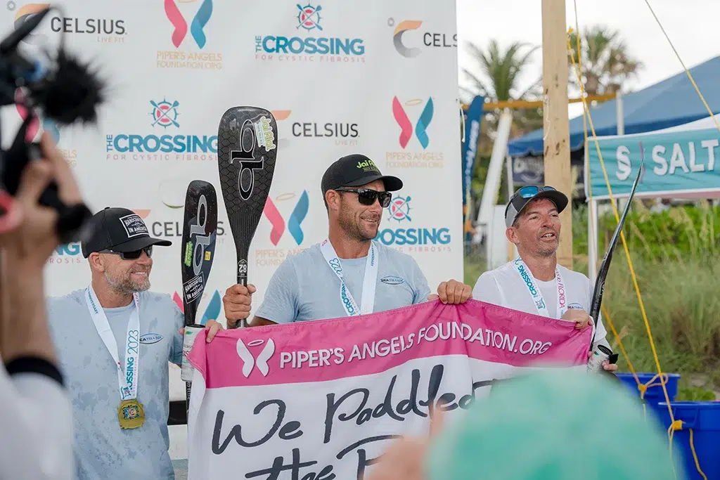 A team celebrates at the beach landing party for the crossing for cystic fibrosis