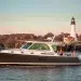 A side profile of the Back Cove 390 yacht at rest in water with a lighthouse and trees as the background