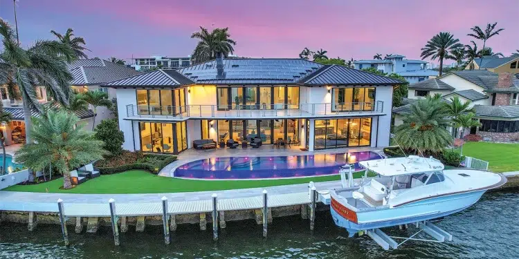 A sustainable waterfront luxury estate with pink and purple sunset behind it