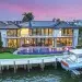 A sustainable waterfront luxury estate with pink and purple sunset behind it