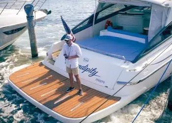 A man standing on his yacht's swim platform while using the wireless yacht controller to dock