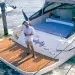 A man standing on his yacht's swim platform while using the wireless yacht controller to dock