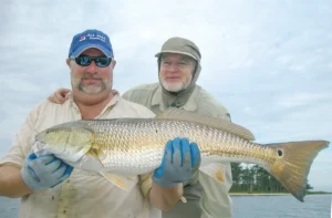 Two men hold up a Redfish
