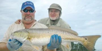 Two men hold up a Redfish