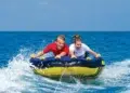 two people are towed on a tube behind a boat