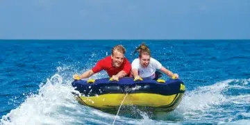 two people are towed on a tube behind a boat
