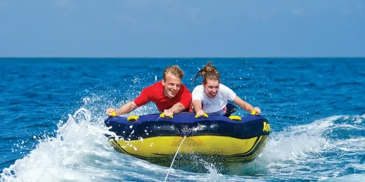 two people are towed on a tube behind a boat
