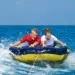 two people are towed on a tube behind a boat
