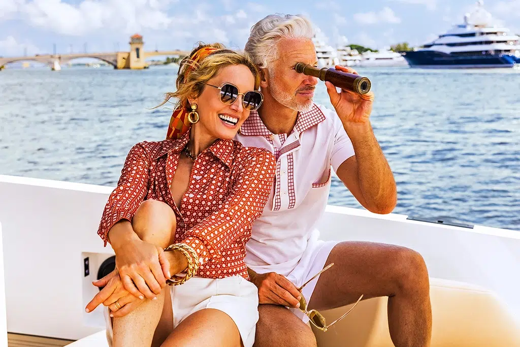 A couple sits on the bow of a yacht leaning into each other