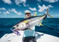 Angler holding a big yellowfin tuna on a boat.