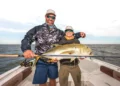 Smiling anglers holding the big jack crevalle they caught.
