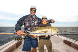 Smiling anglers holding the big jack crevalle they caught.