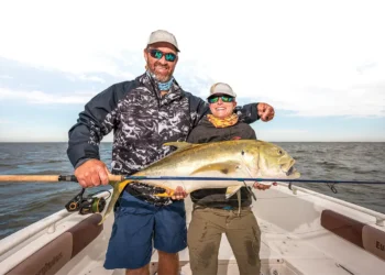 Smiling anglers holding the big jack crevalle they caught.