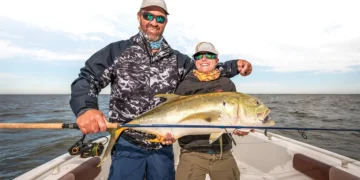 Smiling anglers holding the big jack crevalle they caught.