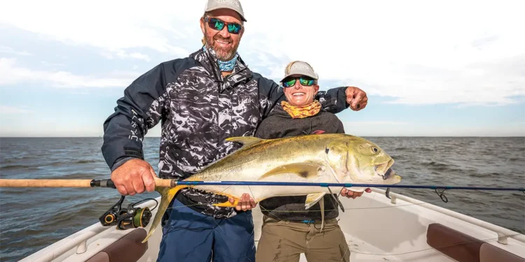 Smiling anglers holding the big jack crevalle they caught.