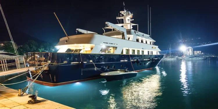 Yacht on the water lit up with boat safety lighting at night.