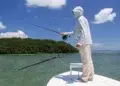 Man on bow using summer fishing tips as he casts his line