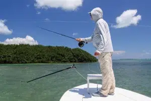 Man on bow using summer fishing tips as he casts his line