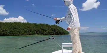 Man on bow using summer fishing tips as he casts his line