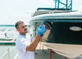 Man cleaning hull of boat with a buffer