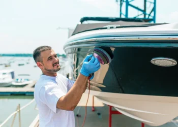 Man cleaning hull of boat with a buffer