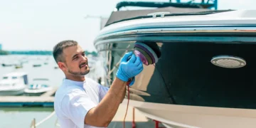 Man cleaning hull of boat with a buffer