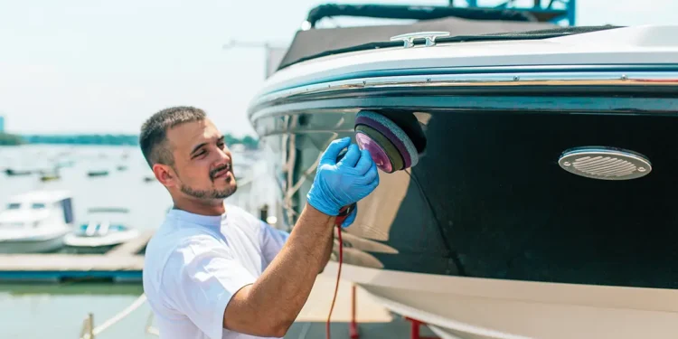 Man cleaning hull of boat with a buffer