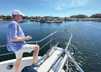 Man on the bow of his boat controlling his docking with a remote