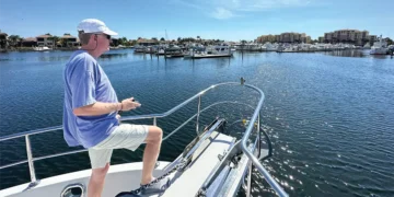 Man on the bow of his boat controlling his docking with a remote