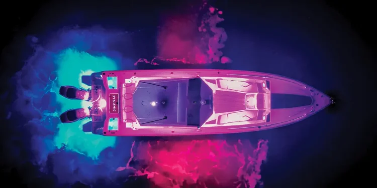 aerial shot of boat in the water at night lit up in rainbow colors with LED lights